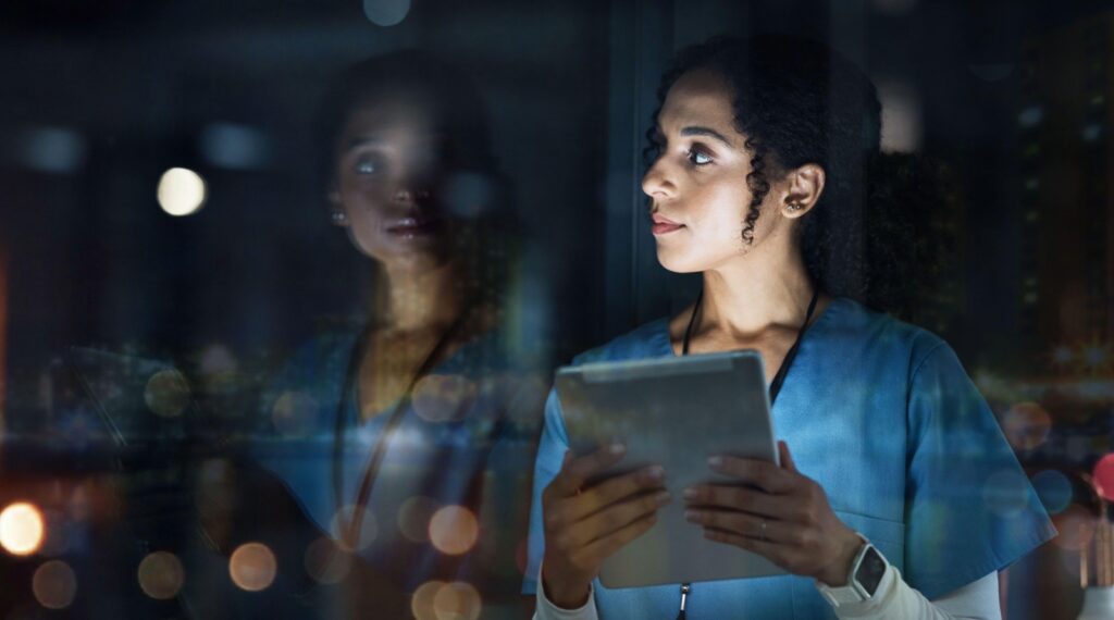Doctor looks at an iPad in hospital at night