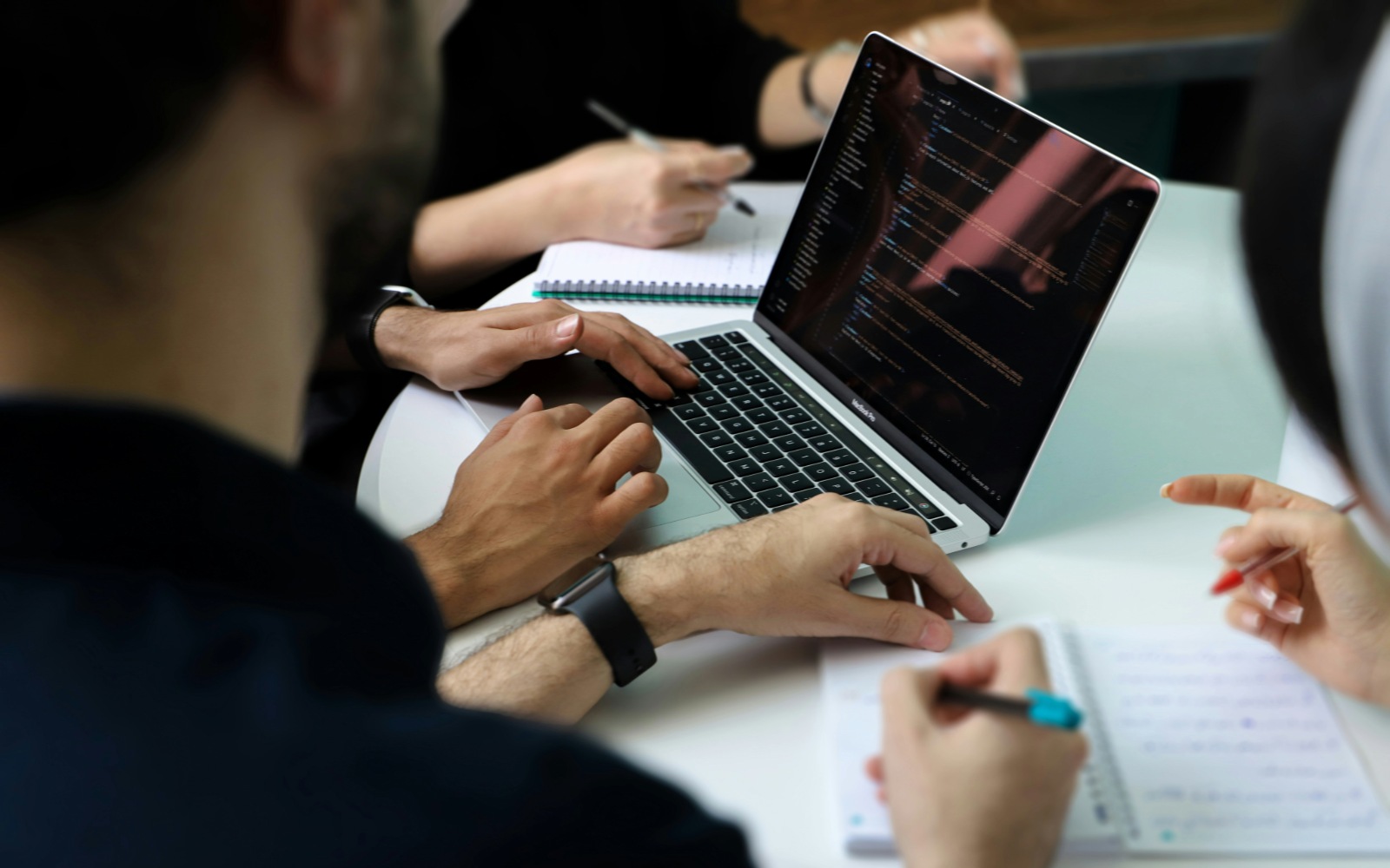 Workers collaborate around a laptop