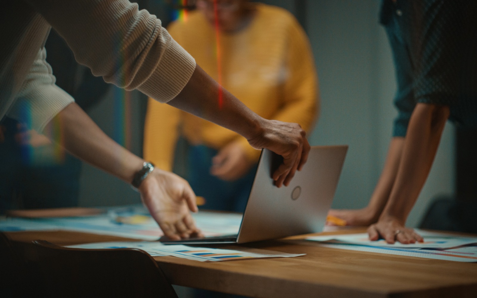 Workers collaborate around a meeting table with technology