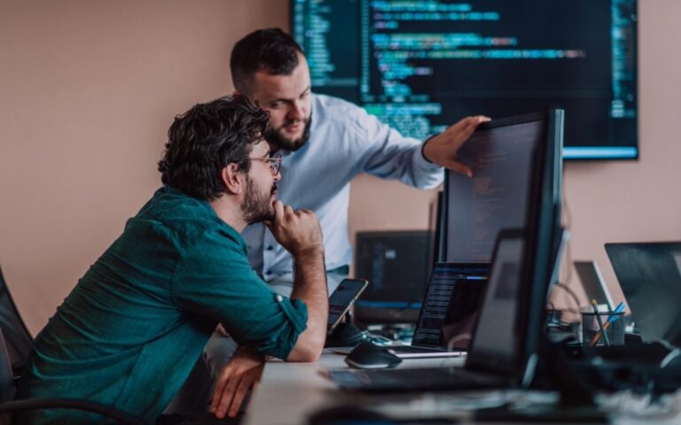 Two workers collaborate at a screen